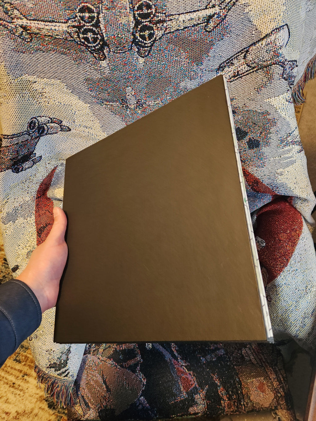 Hand holding the back of the foldable Wildfire Mayhem game board on a decorative fabric
