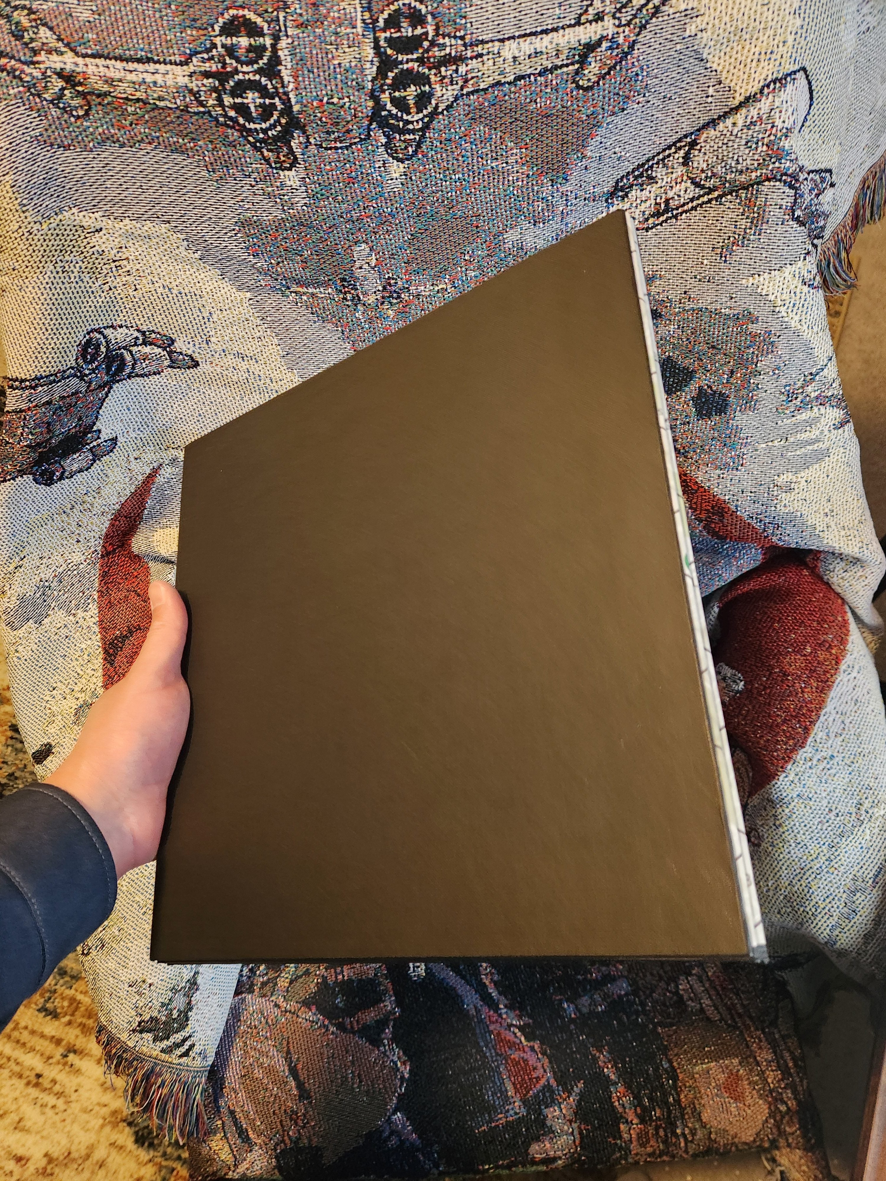 Hand holding the back of the foldable Wildfire Mayhem game board on a decorative fabric
