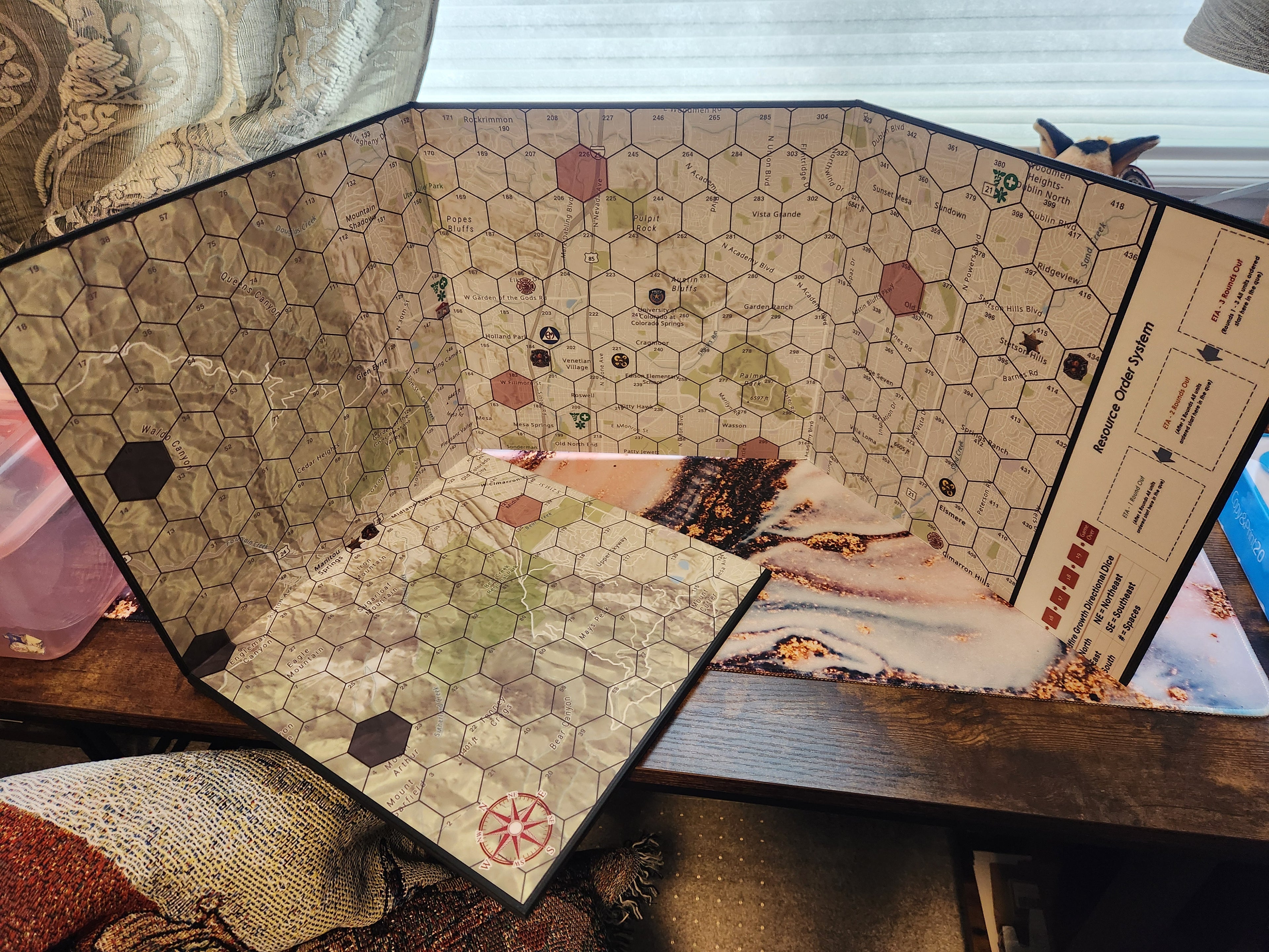 Hard cardboard game board with hex-grid map and wildfire mayhem design on a table
