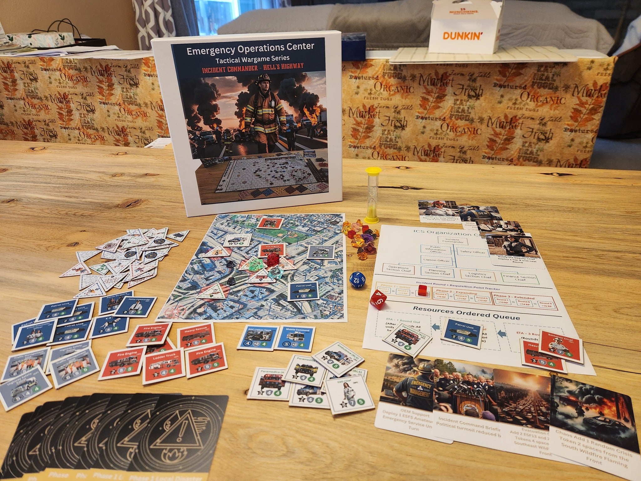 Game setup showing the Incident Commander Hell's Highway board, cards, tokens, sand timer, and scenario sheets on a wooden table.