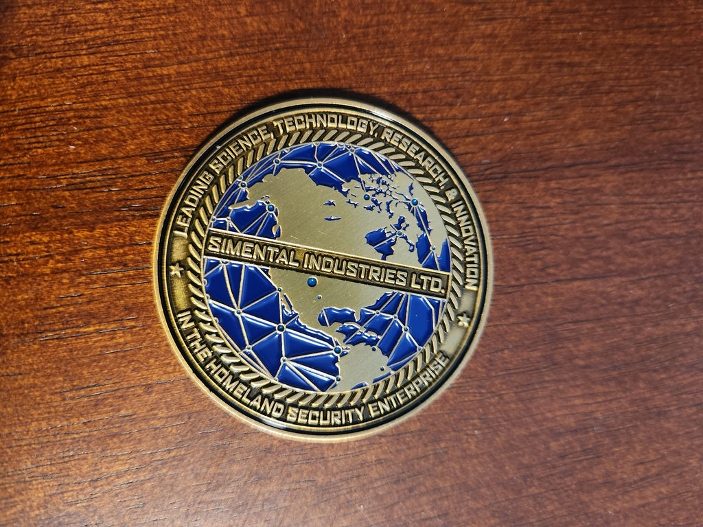 Close-up of the Limited Edition Disaster Gaming Challenge Coin front side showing a blue world map design and 'Simental Industries Ltd.' banner on a wooden surface